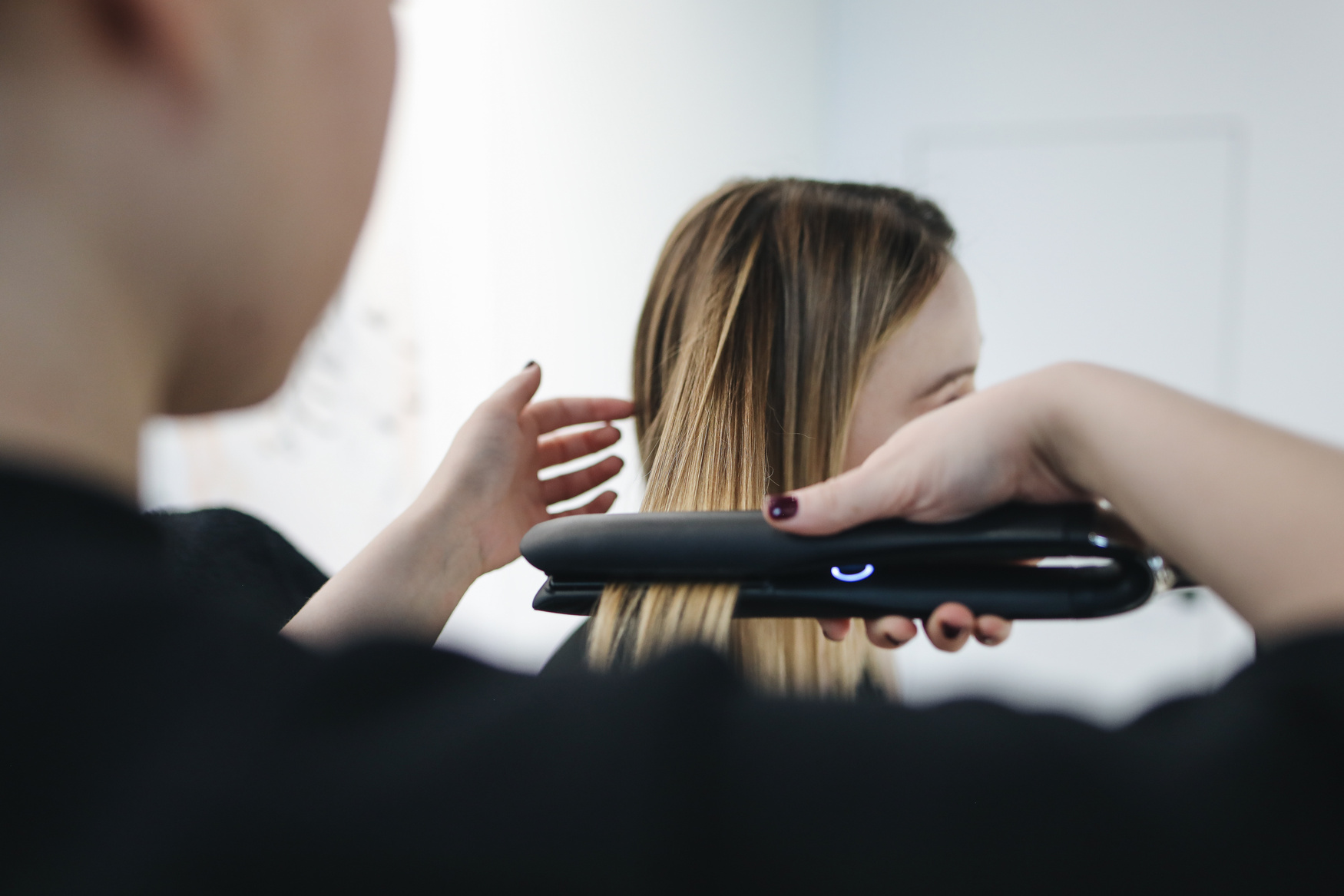 Selective Focus Photo of Person Ironing a Woman's Hair